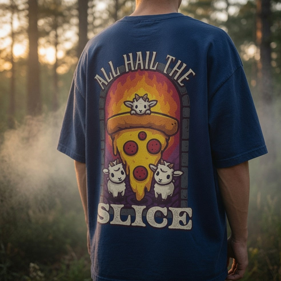 Person wearing a blue t-shirt with a pizza graphic and text 'All Hail The Slice' in a forest setting.