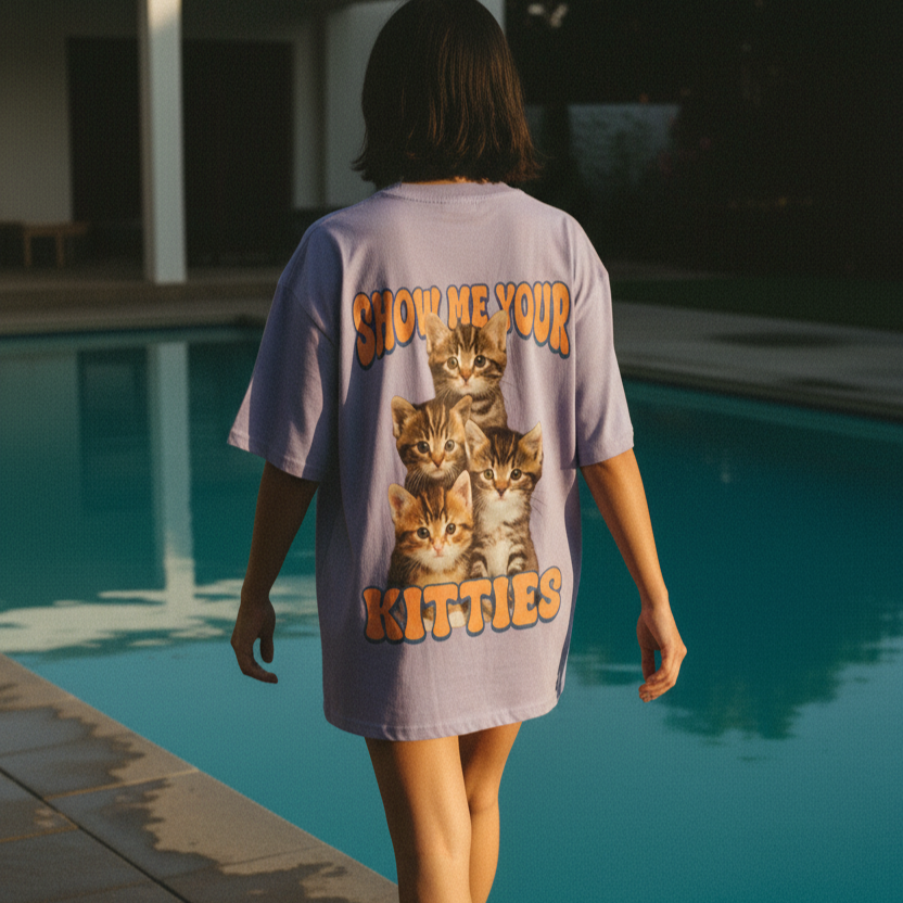 Woman wearing a oversized t-shirt with cat graphics and "Show me your Kitties" slogan, by a pool