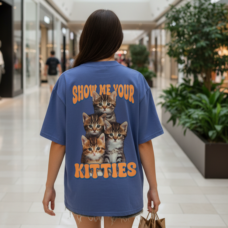Woman wearing a blue t-shirt with cat illustrations and text in a mall setting